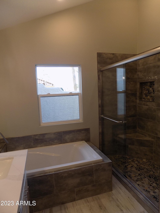 bathroom with plus walk in shower, hardwood / wood-style floors, and vanity