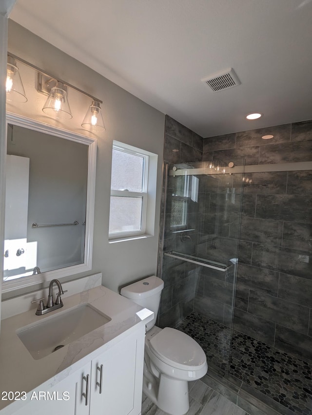 bathroom with a shower with shower door, tile floors, toilet, and vanity