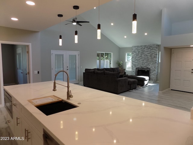 kitchen with decorative light fixtures, a fireplace, sink, and light stone counters