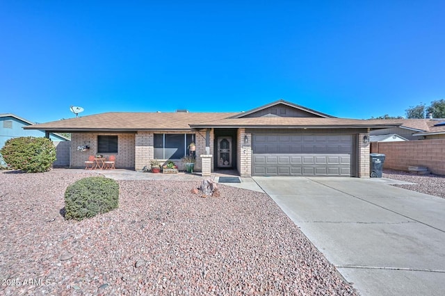 ranch-style house with driveway, brick siding, an attached garage, and fence