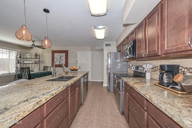 kitchen featuring visible vents, a sink, stainless steel appliances, light tile patterned flooring, and decorative backsplash