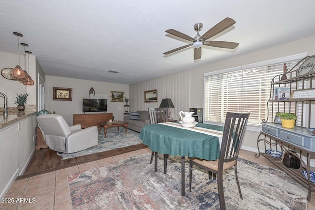 dining room featuring a textured ceiling, light tile patterned floors, baseboards, and ceiling fan