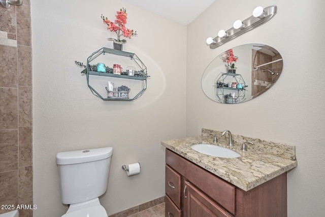 full bathroom featuring tiled shower, toilet, and vanity