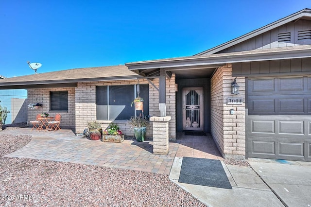 view of exterior entry with brick siding and a garage