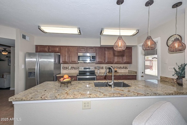 kitchen featuring visible vents, backsplash, light stone countertops, stainless steel appliances, and a sink