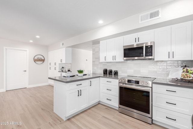 kitchen with decorative backsplash, stainless steel appliances, kitchen peninsula, and white cabinets