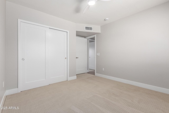 unfurnished bedroom with light colored carpet, ceiling fan, and a closet