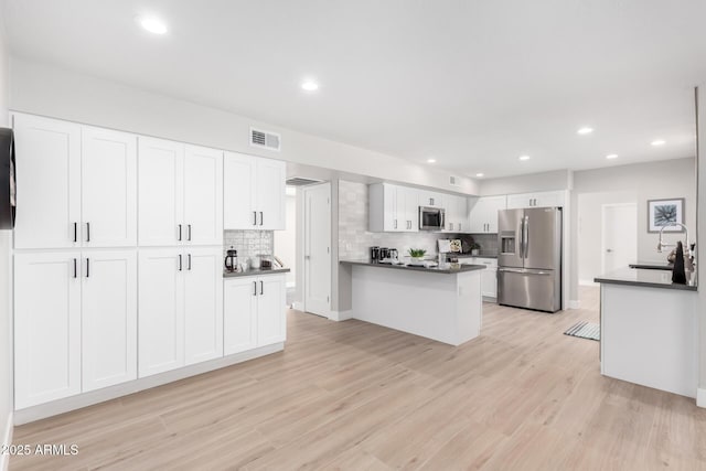 kitchen with stainless steel appliances, white cabinetry, sink, and light hardwood / wood-style flooring