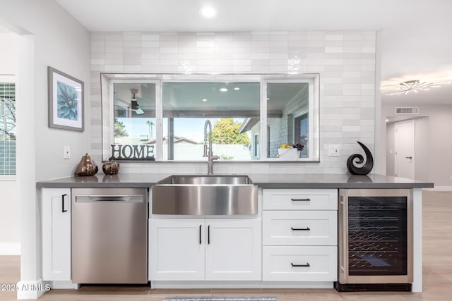 bar with beverage cooler, dishwasher, sink, and white cabinets