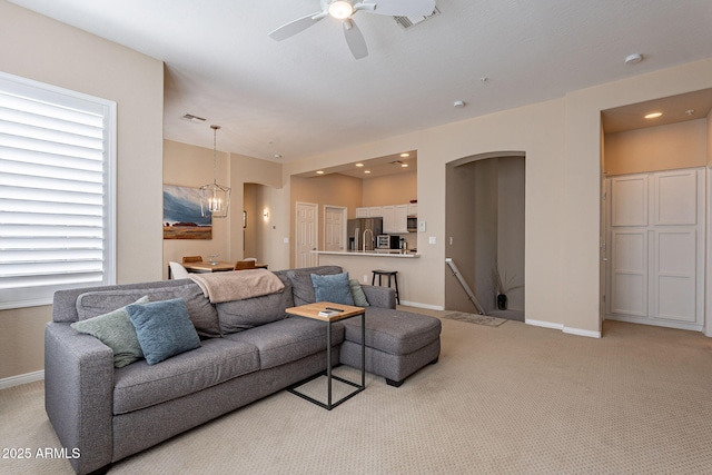 carpeted living room featuring ceiling fan with notable chandelier