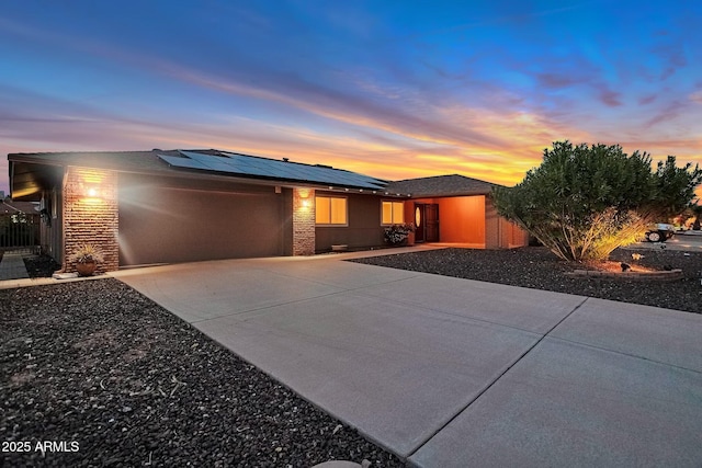 view of front of property with solar panels, an attached garage, driveway, and stucco siding