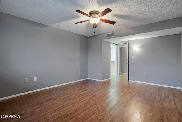 empty room with visible vents, baseboards, wood finished floors, a textured ceiling, and a ceiling fan