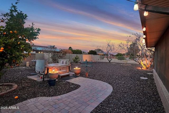 patio terrace at dusk featuring a fenced backyard and a playground