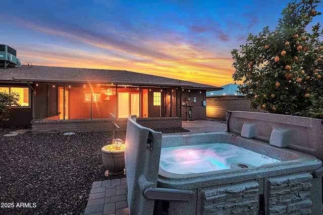 pool at dusk featuring a patio area, cooling unit, a hot tub, and fence