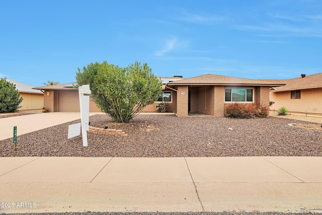 view of front facade with concrete driveway, an attached garage, and brick siding