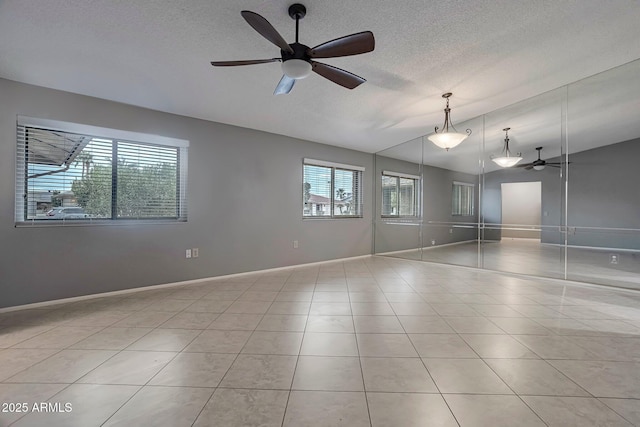 empty room with light tile patterned floors, a textured ceiling, lofted ceiling, and ceiling fan