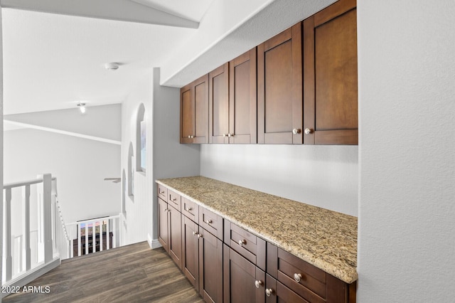 kitchen with light stone countertops, dark hardwood / wood-style floors, and lofted ceiling