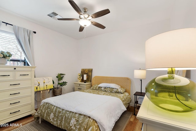 bedroom with dark wood finished floors, visible vents, and a ceiling fan