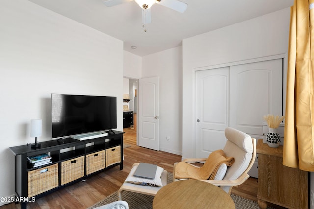 living room featuring ceiling fan, baseboards, and wood finished floors