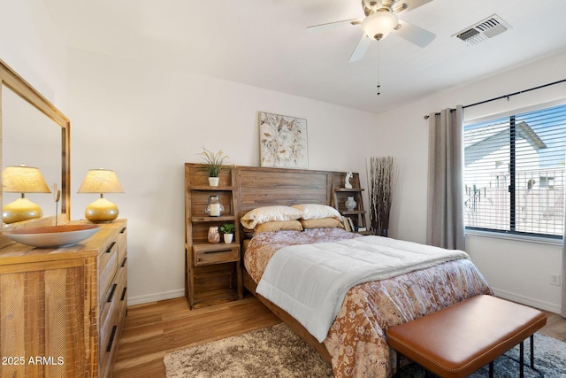 bedroom featuring light wood-style flooring, a ceiling fan, visible vents, and baseboards