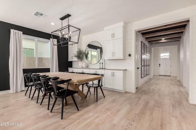 dining room featuring beamed ceiling, a chandelier, a wealth of natural light, and light wood-type flooring