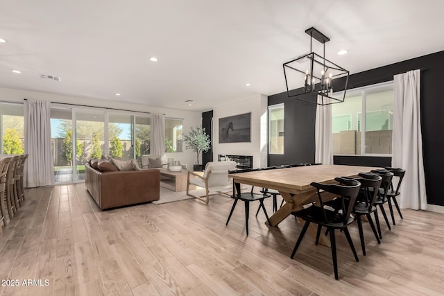 dining room with plenty of natural light, a large fireplace, and light wood-type flooring