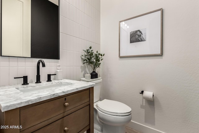 bathroom featuring vanity, toilet, and decorative backsplash