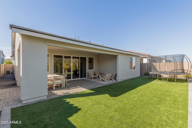 rear view of property with a yard, a patio area, a trampoline, and central air condition unit