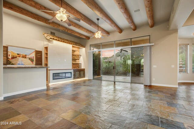 35824 N Tom Darlington Dr, Carefree, AZ 85377 - unfurnished living room with stone tile flooring, a ceiling fan, healthy amount of natural light, and beamed ceiling