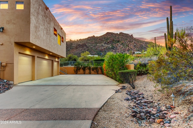 35824 N Tom Darlington Dr, Carefree, AZ 85377 - property exterior at dusk featuring a mountain view, a garage, stucco siding, concrete driveway, and fence