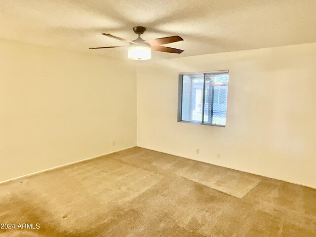 spare room with ceiling fan, a textured ceiling, and carpet