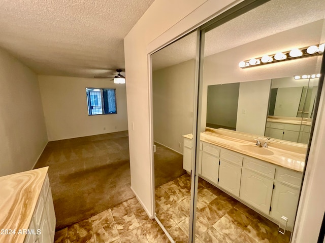 bathroom featuring ceiling fan, vanity, and a textured ceiling