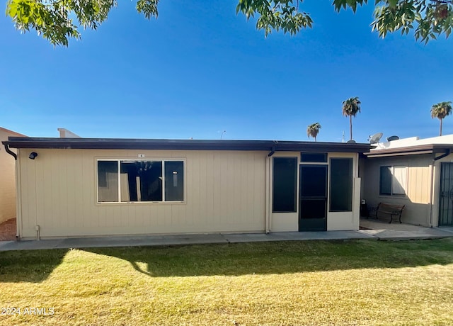 back of property featuring a lawn and a patio