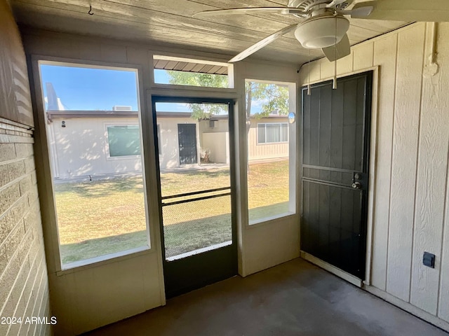 entryway featuring ceiling fan, wooden walls, wood ceiling, and concrete floors