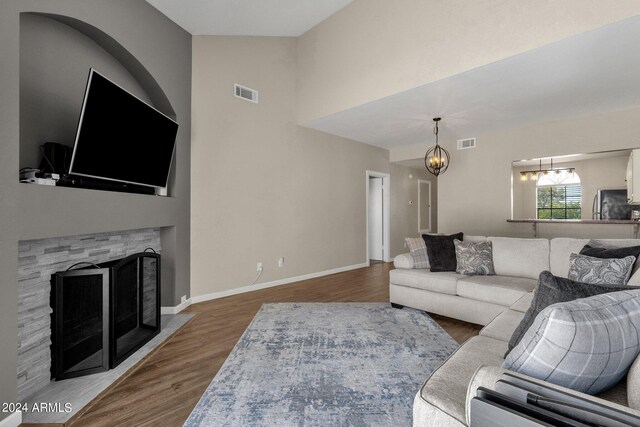 living room with a notable chandelier, vaulted ceiling, and wood-type flooring