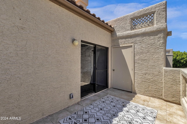 property entrance with a patio area, a tile roof, and stucco siding