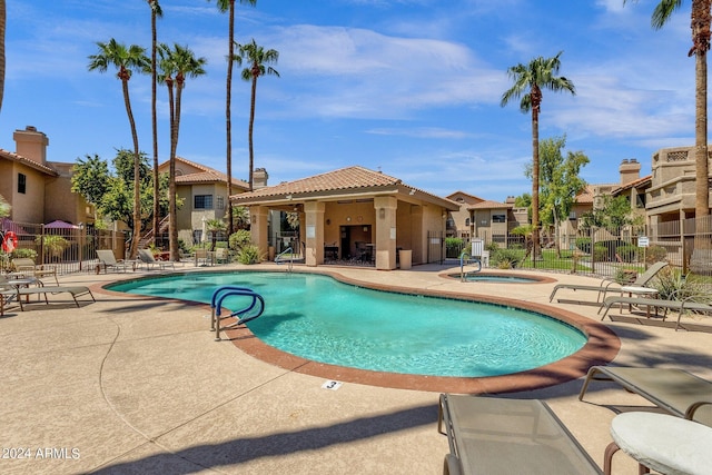 community pool with a residential view, a patio, a hot tub, and fence