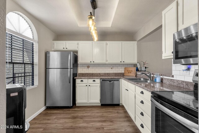 kitchen with tasteful backsplash, decorative light fixtures, dark wood-type flooring, and stainless steel appliances