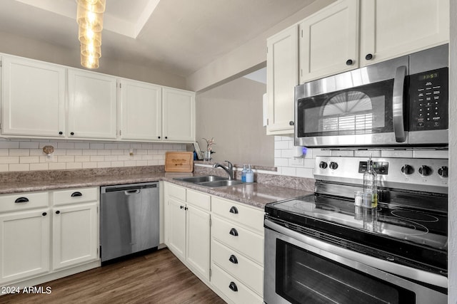 kitchen with dark wood-style flooring, tasteful backsplash, appliances with stainless steel finishes, white cabinetry, and a sink