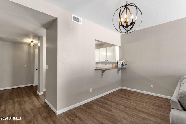 unfurnished dining area featuring dark wood-style floors, an inviting chandelier, visible vents, and baseboards