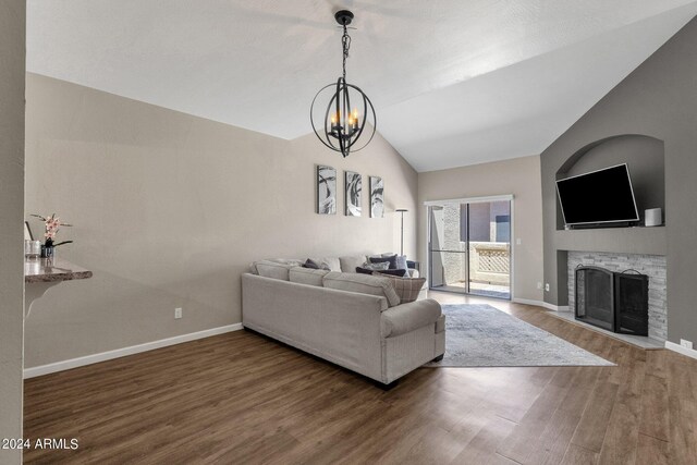 living room featuring lofted ceiling, a chandelier, dark wood-type flooring, and a fireplace