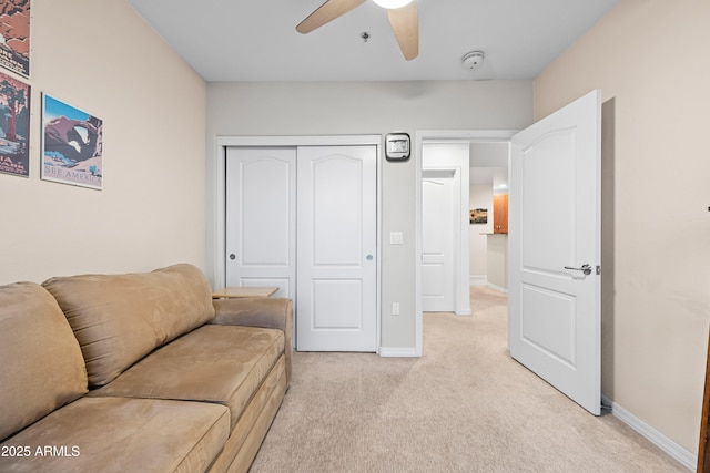 living area with baseboards, a ceiling fan, and light colored carpet