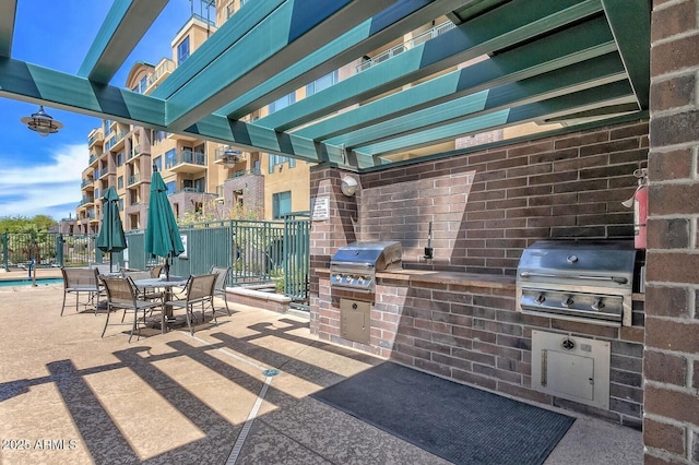 view of patio / terrace with outdoor dining space, fence, an outdoor kitchen, and area for grilling