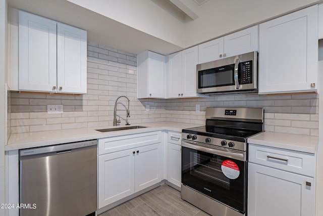 kitchen with stainless steel appliances, white cabinets, light countertops, and a sink