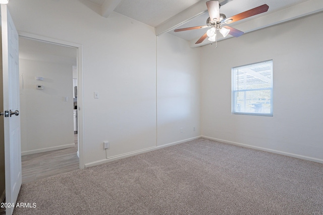 carpeted spare room featuring a ceiling fan, baseboards, and beam ceiling