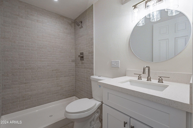 full bathroom featuring tiled shower, vanity, and toilet