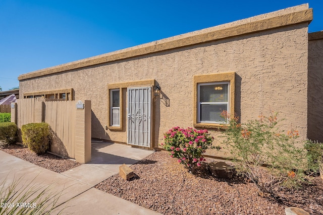 property entrance featuring fence and stucco siding