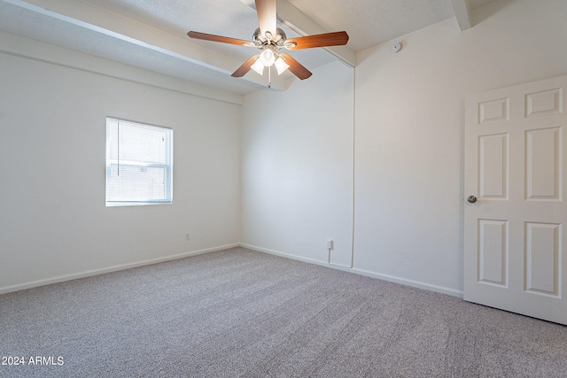 empty room featuring carpet floors, a ceiling fan, baseboards, and beamed ceiling