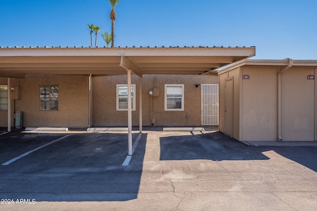 doorway to property featuring covered parking and stucco siding