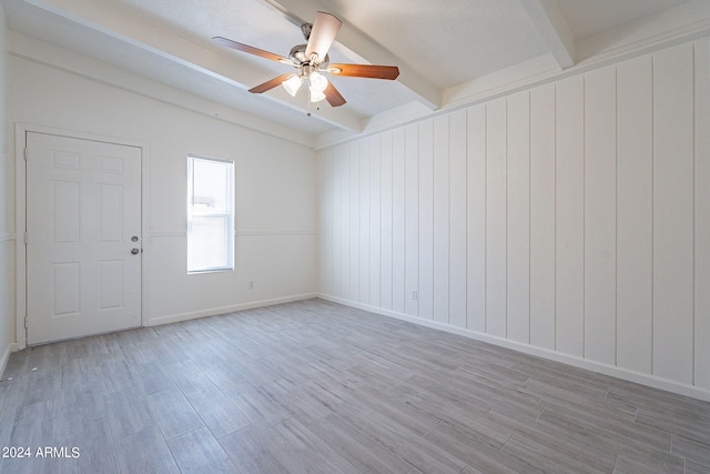 spare room with a textured ceiling, ceiling fan, beamed ceiling, and light wood-type flooring